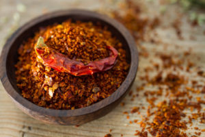 Wooden bowl full of fiery chilli pepper flakes.